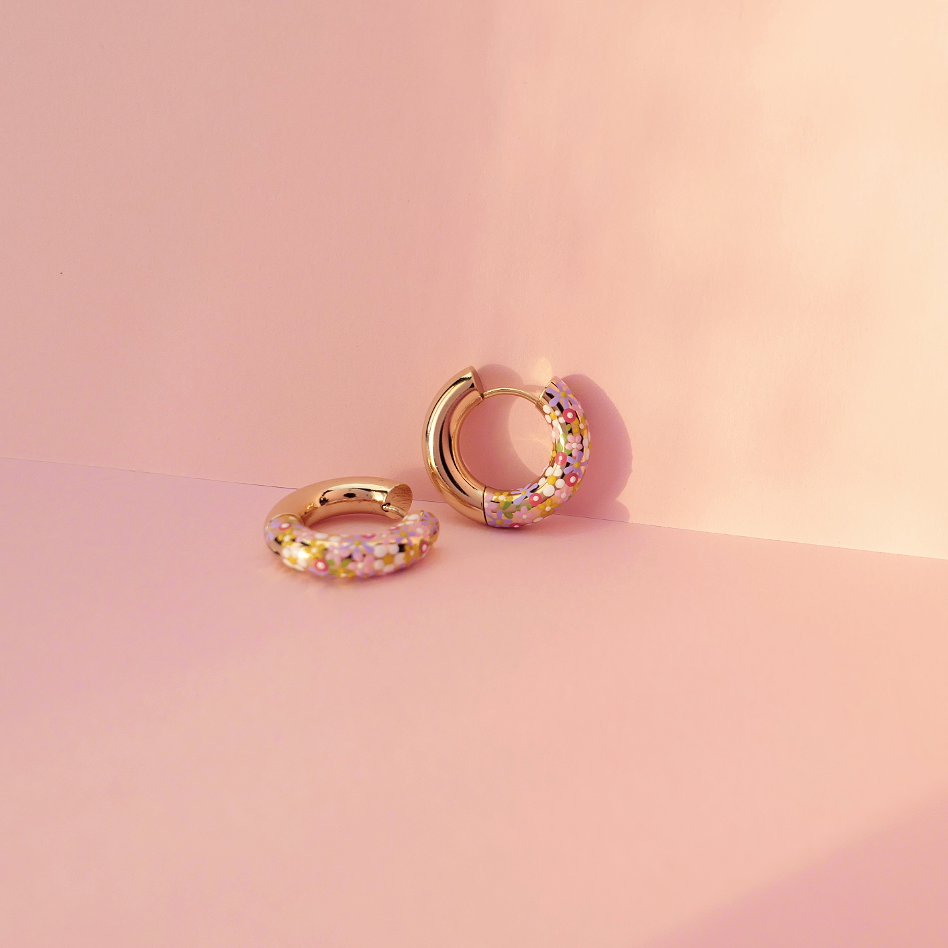 Flower charm hoop earrings in an ear