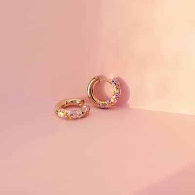 Flower charm hoop earrings in an ear