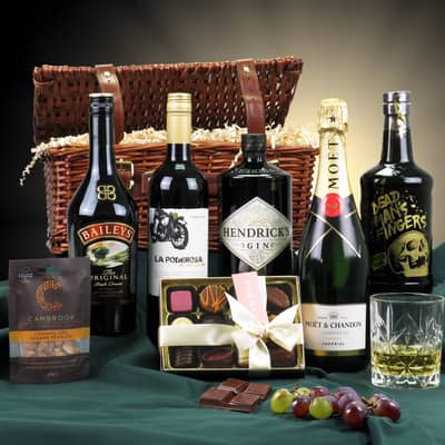 Wicker hamper against a dark gold background with bottles of Baileys, Malbec, Hendrick's Gin and Moet & Chandon Champagne in foreground, with Belgian chocolates