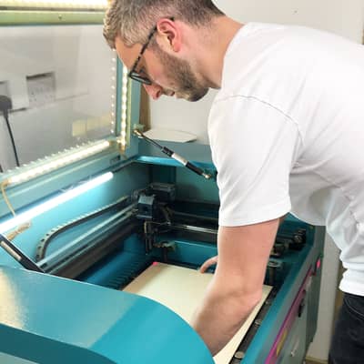 James placing a sheet of plywood into the laser engraver
