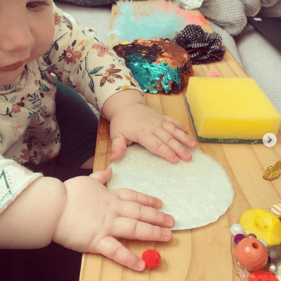 6 month old baby playing with a sensory board