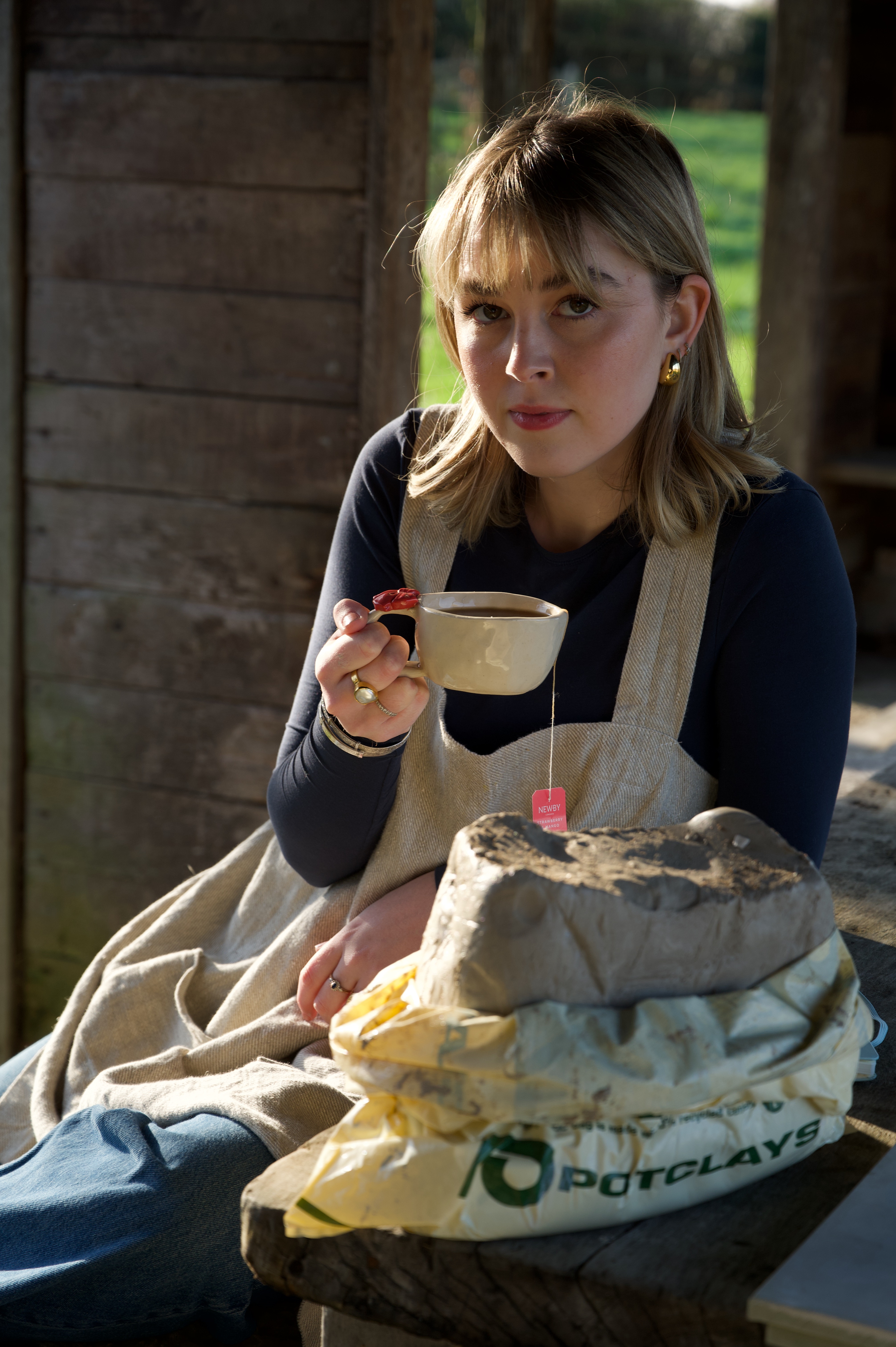 girl holding mug with pottery clay on table