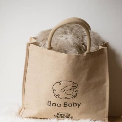Baa Baby jute shopper bag on a pile of fluffy sheepskin pram liners