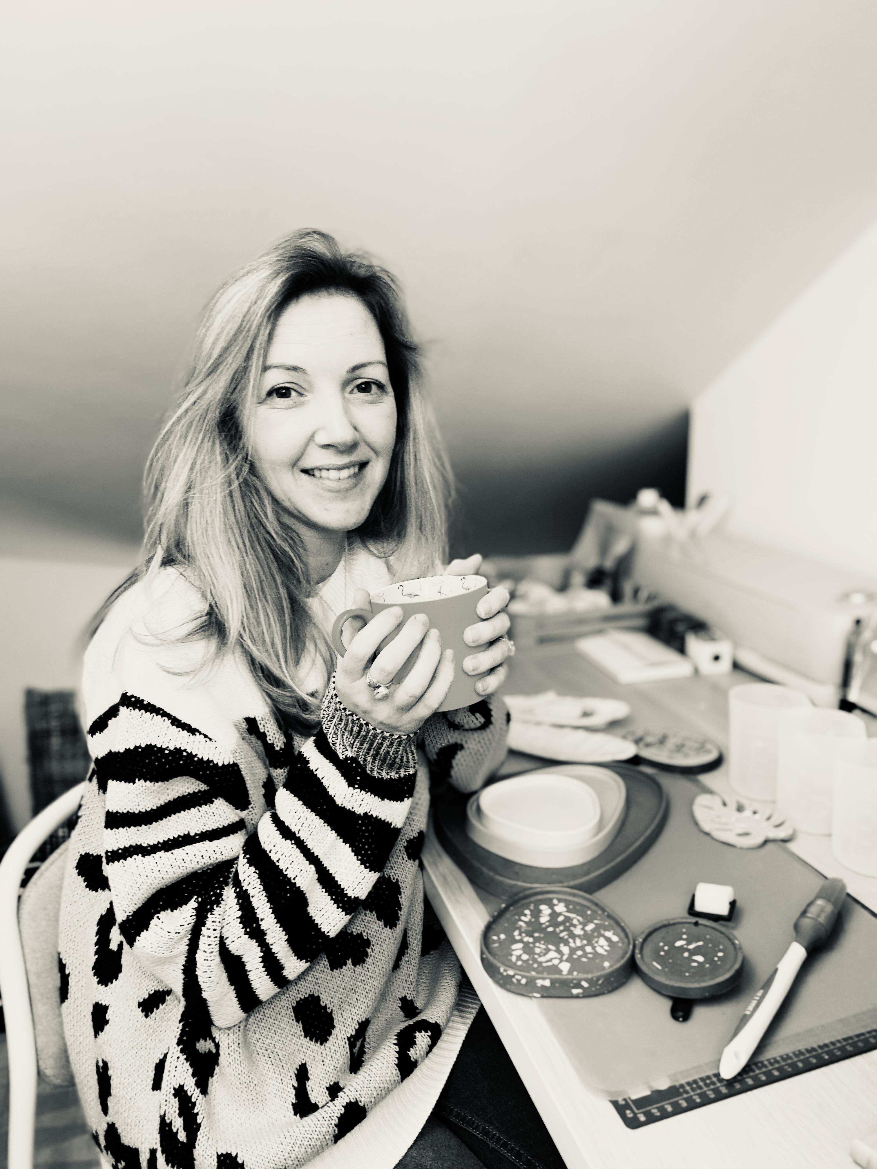 Female sitting at making desk holding a mug