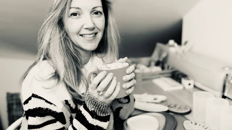Female sitting at making desk holding a mug