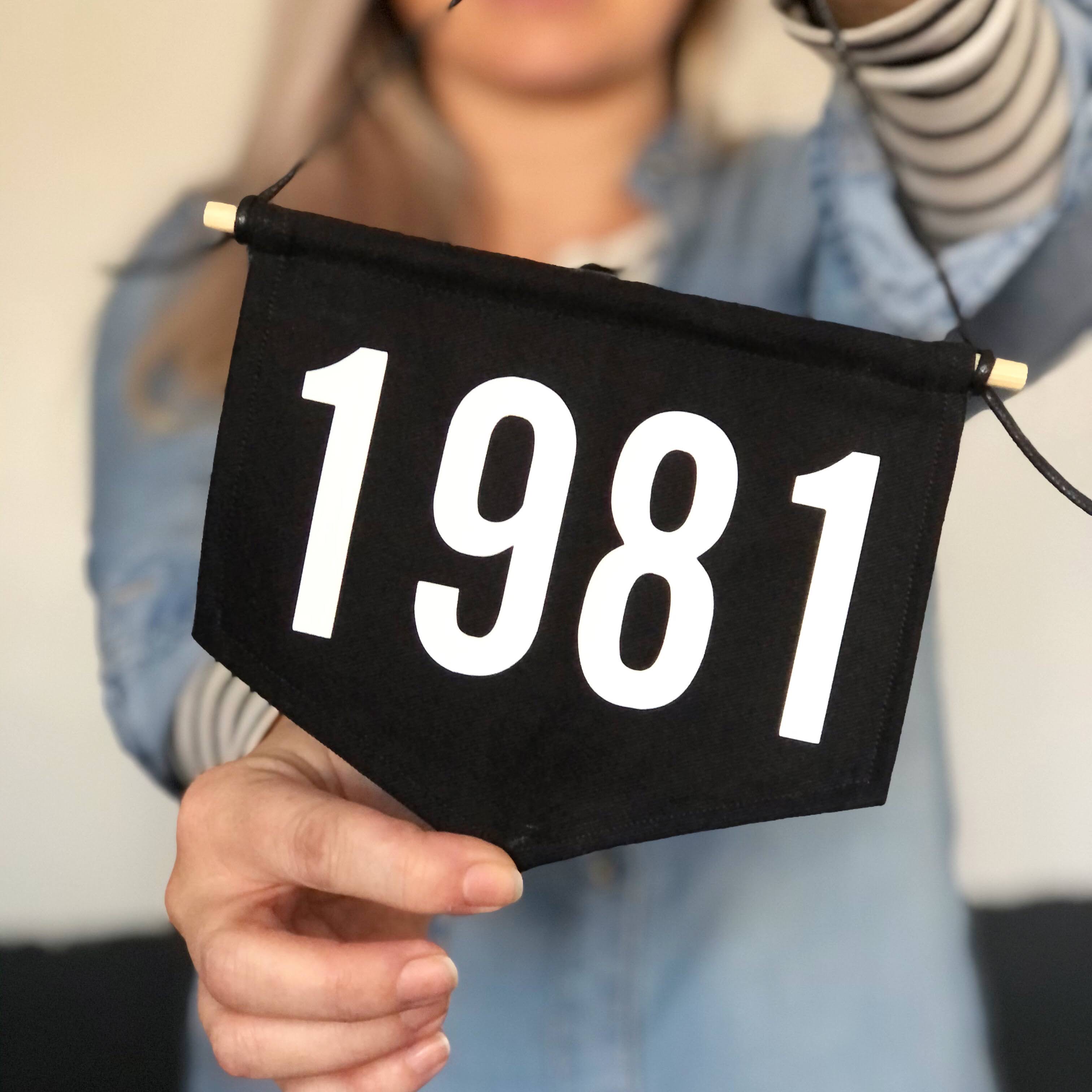 Woman holding a black banner with the year 1981