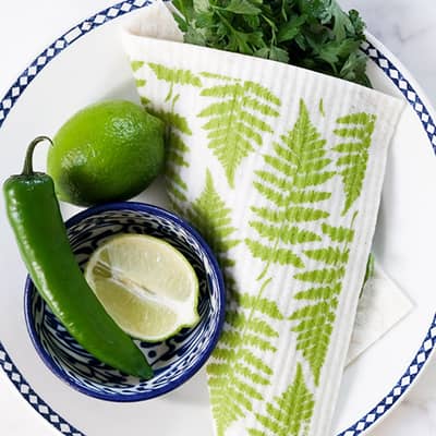 Dishcloth, printed in a green Fern design, wrapped around washed parsley on a plate.