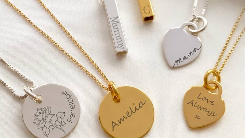 A range of personalised silver and gold necklace displayed with a gift bag & dried flowers