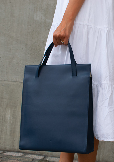 Navy Blue Adjustable tote bag held in hand. It can also be extended over the shoulder