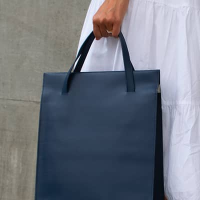 Navy Blue Adjustable tote bag held in hand. It can also be extended over the shoulder
