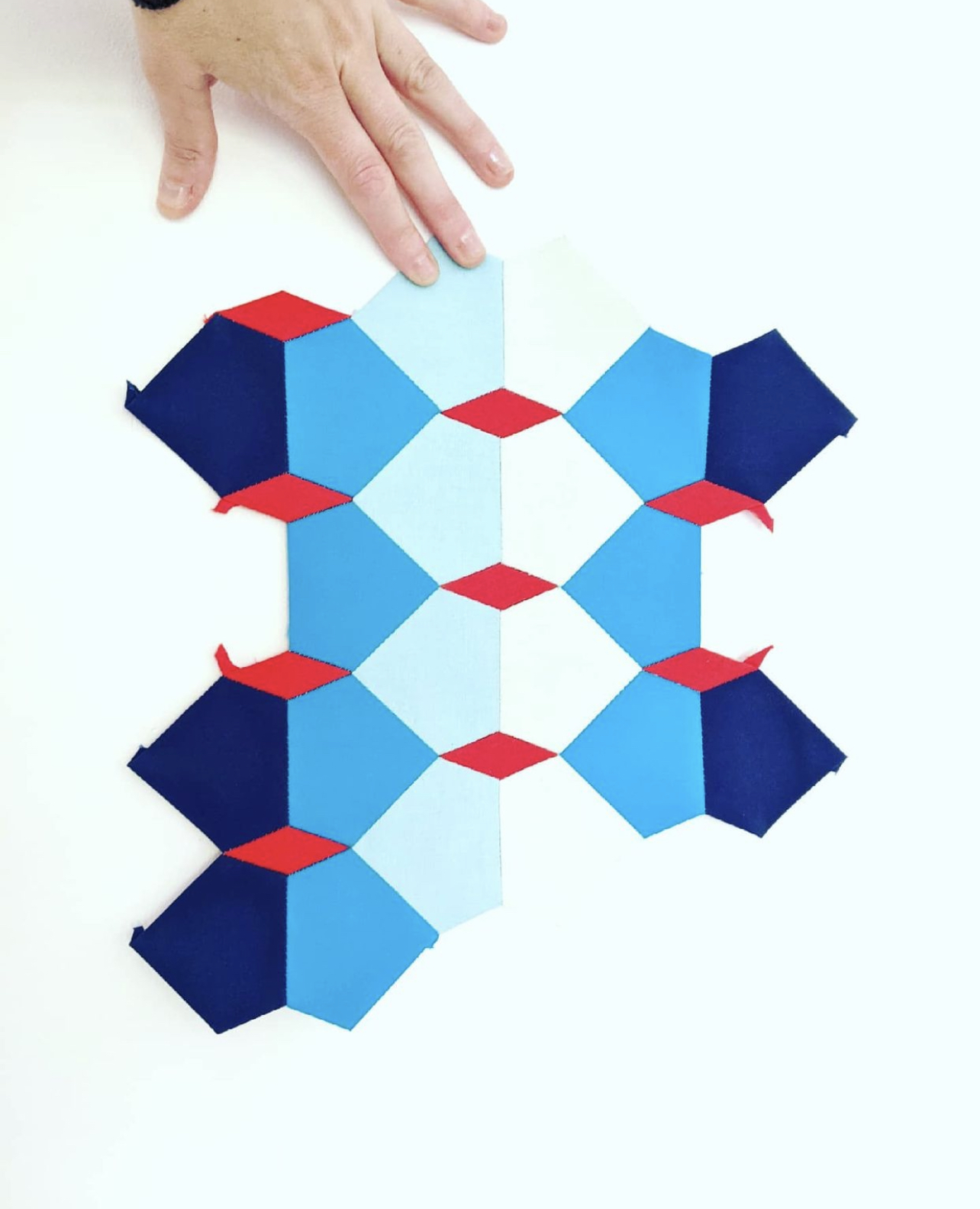 English paper pieced section of a quilt in blues and red