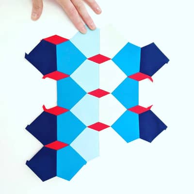 English paper pieced section of a quilt in blues and red