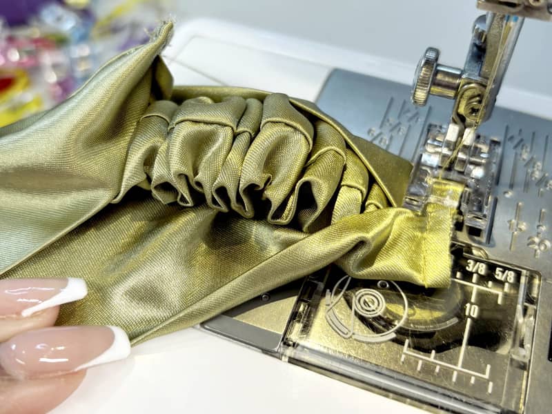 green satin fabric on sewing machine close up