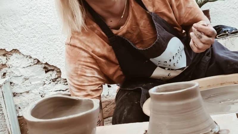 happy pottery class participant making a pot on the potter's wheel