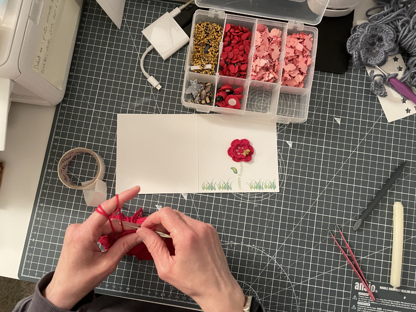 An image of Njomza, co-founder of Nyoki Handmade, crafting crochet flowers with organic yarn to embellish birthday cards.