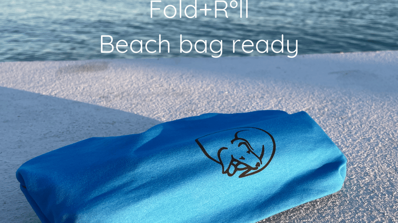 A blue Fold+Roll which is a fabric organiser containing some clothes with a sea view