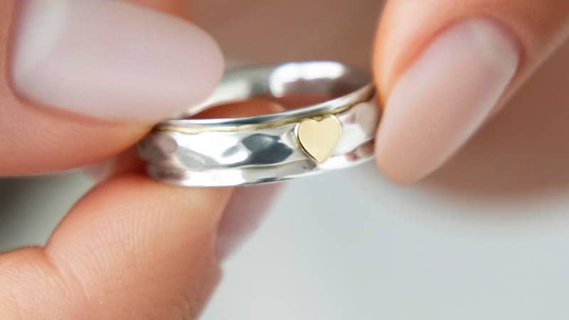Elegant narrow silver spinner ring, beautifully crafted with a dainty heart detail for a romantic touch.