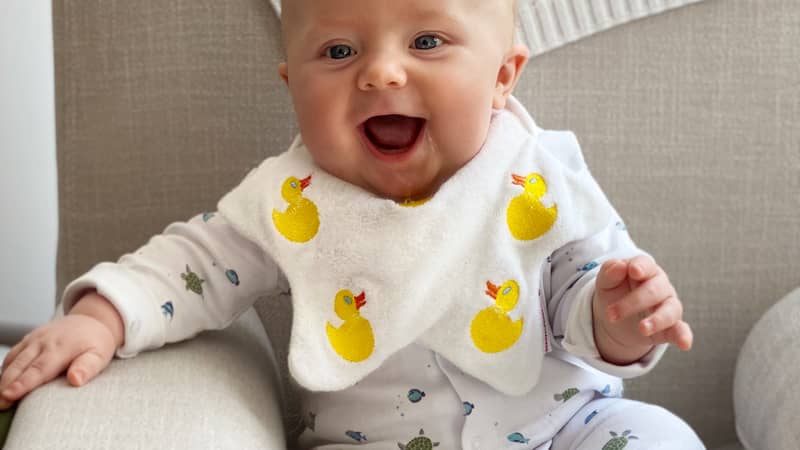 Baby wearing a Dribble Days bib embroidered with Ducks