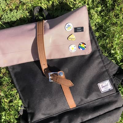 Displayed is a pink and black rucksack with a selection of enamel pins from Elle&Co on the front.