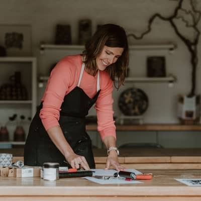 Image of Kirsty Hall making inking up a print block.