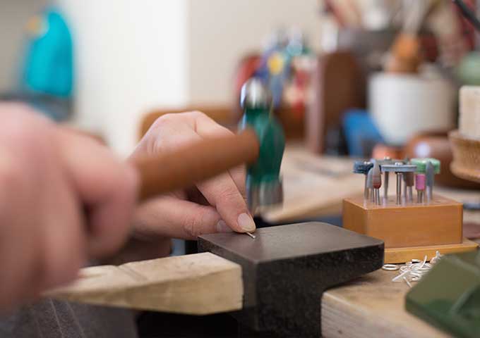 Hammering silver jewellery in the studio