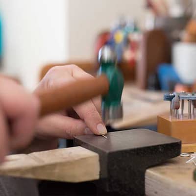 Hammering silver jewellery in the studio