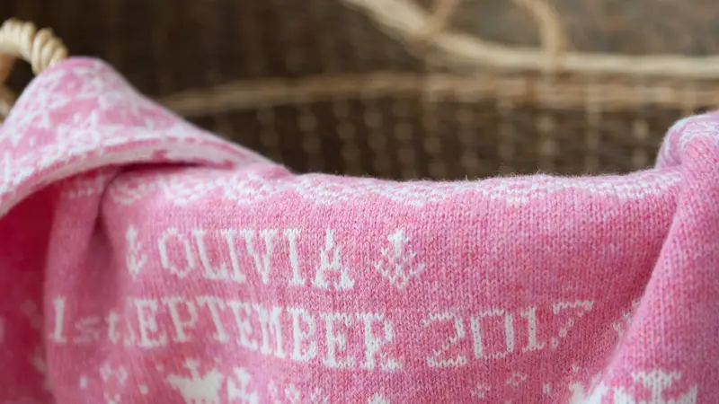 pink baby blanket draped over baby basket