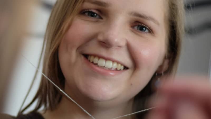 white woman holding up saturn planet necklace and wearing earth blue earrings