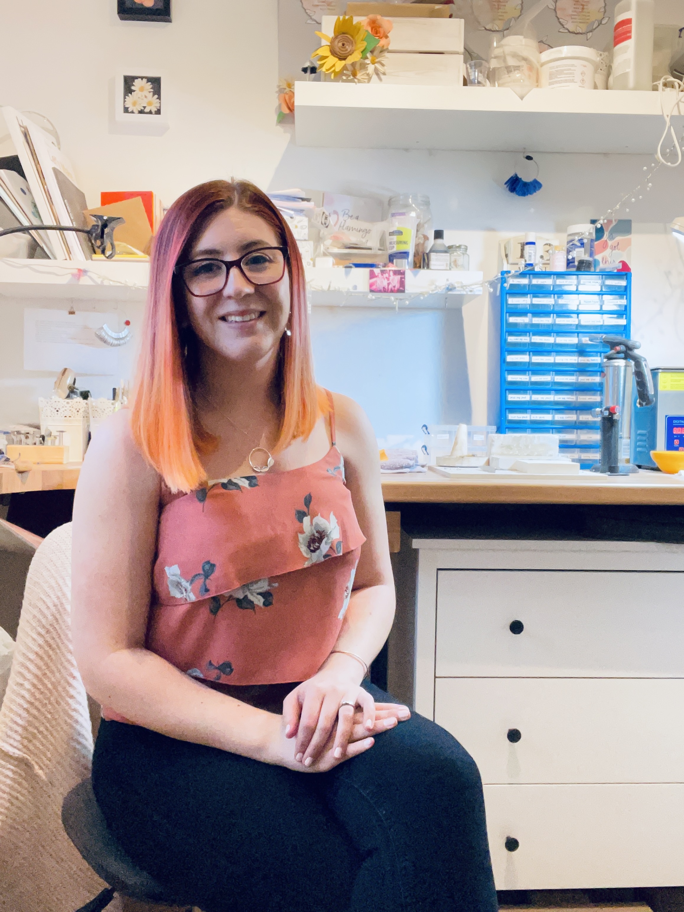 Jen Lithgo - Jen smiling, while sat with her back to her jewellery work bench