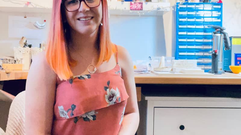 Jen Lithgo - Jen smiling, while sat with her back to her jewellery work bench