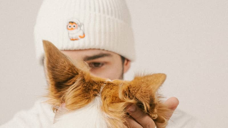 Men in embroidered beanie with cat embroidery petting a dog