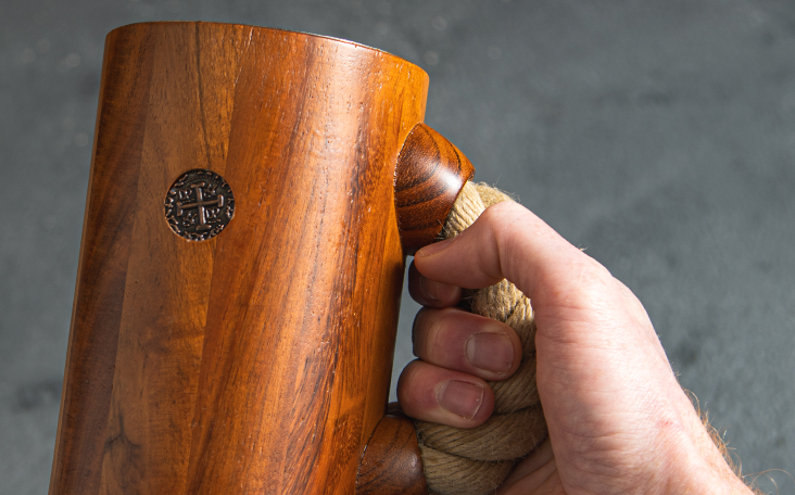 close up of chuug wooden beer tankard viking pirate metal coin replica and black rope handle on the side