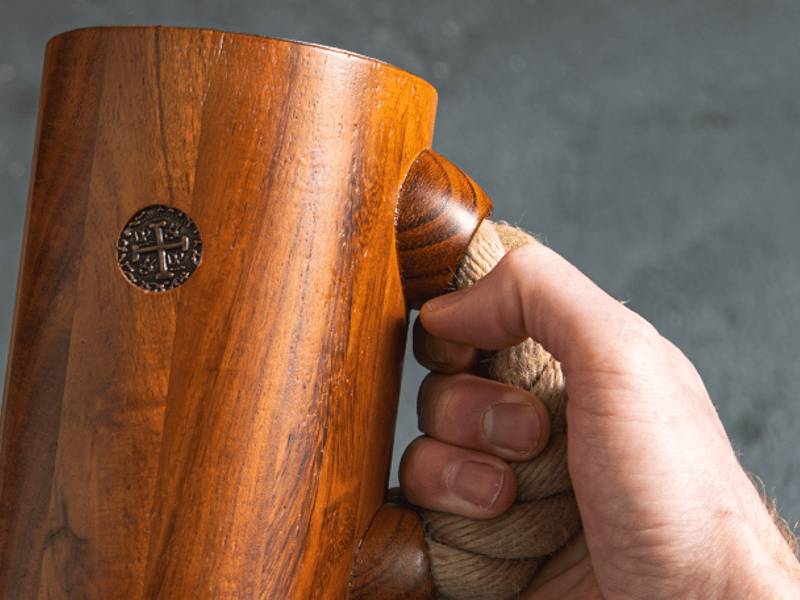 close up of chuug wooden beer tankard viking pirate metal coin replica and black rope handle on the side