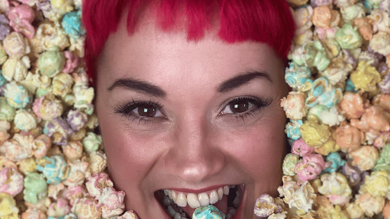 A Ladies head with red hair and buried in Rainbow popcorn