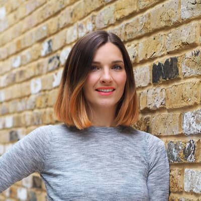 A woman with brown hair standing by a wall