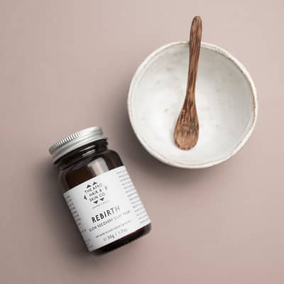 A small jar of rebirth flat mask with a ceramic bowl and wooden spoon