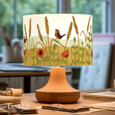 Freshly made wren lampshade by Ceridwen Hazelchild, featuring British woodland bird illustration, in a softly lit art studio.