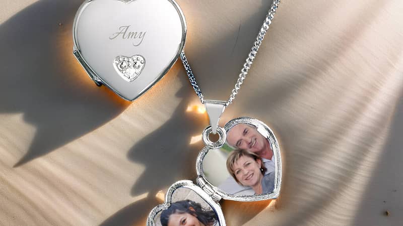 Sterling silver heart locket necklace personalised with photos and name, displayed on soft sand.