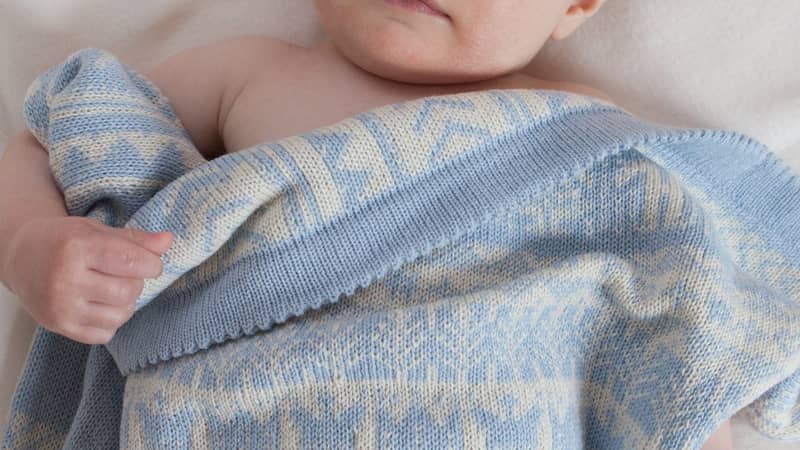 baby lying under cashmere blanket