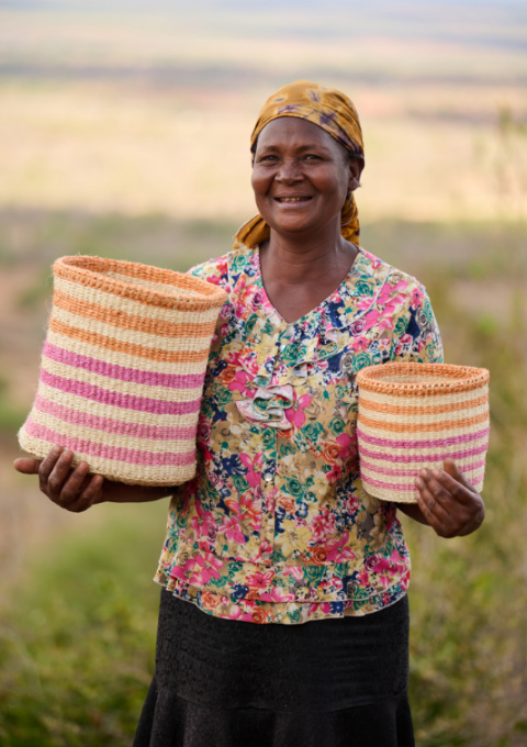 The Basket Room Female Kenyan Basket Weaver Holding Colourful Basket