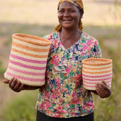 The Basket Room Female Kenyan Basket Weaver Holding Colourful Basket