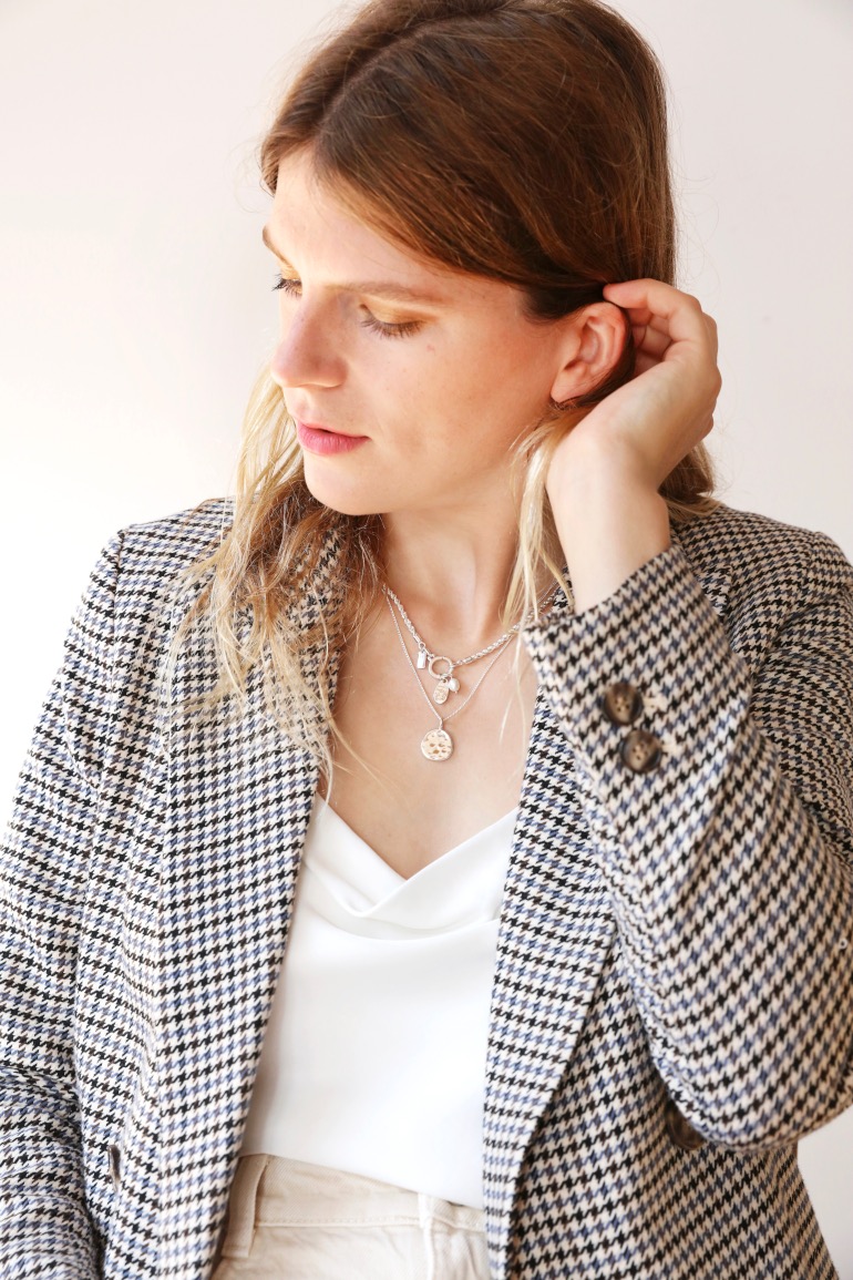 Model wearing two tala lani necklaces layered brushing hair behind their ear