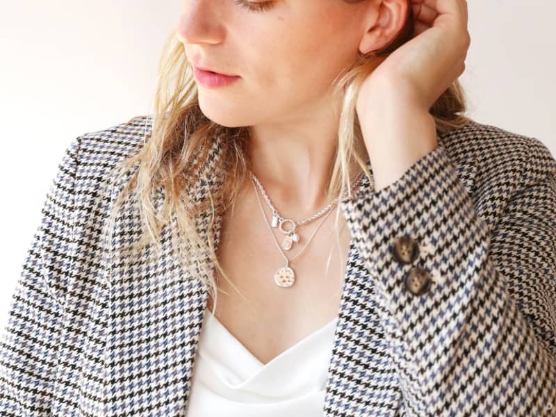 Model wearing two tala lani necklaces layered brushing hair behind their ear