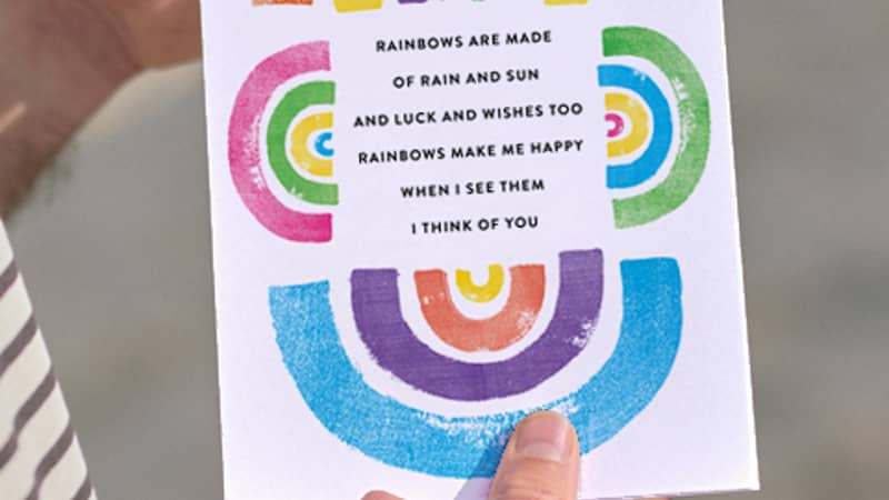 Two hands holding a poem about friendship surrounded by rainbows