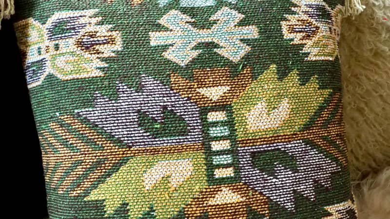A southwestern green cushion with aztec leaf pattern