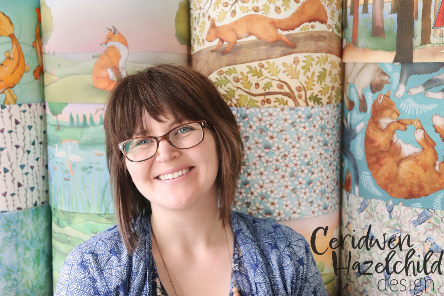 Ceridwen Hazelchild standing in front of her handmade illustrated lampshades, nature-inspired lighting for cosy homes and children's rooms.