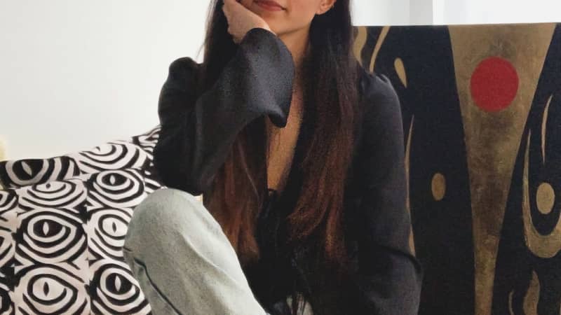 Chromakane multiethnic Eurasian female artist headshot in studio with canvas painting and cushions in background