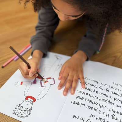 Girl lying on the floor colouring in a child in a colouring book