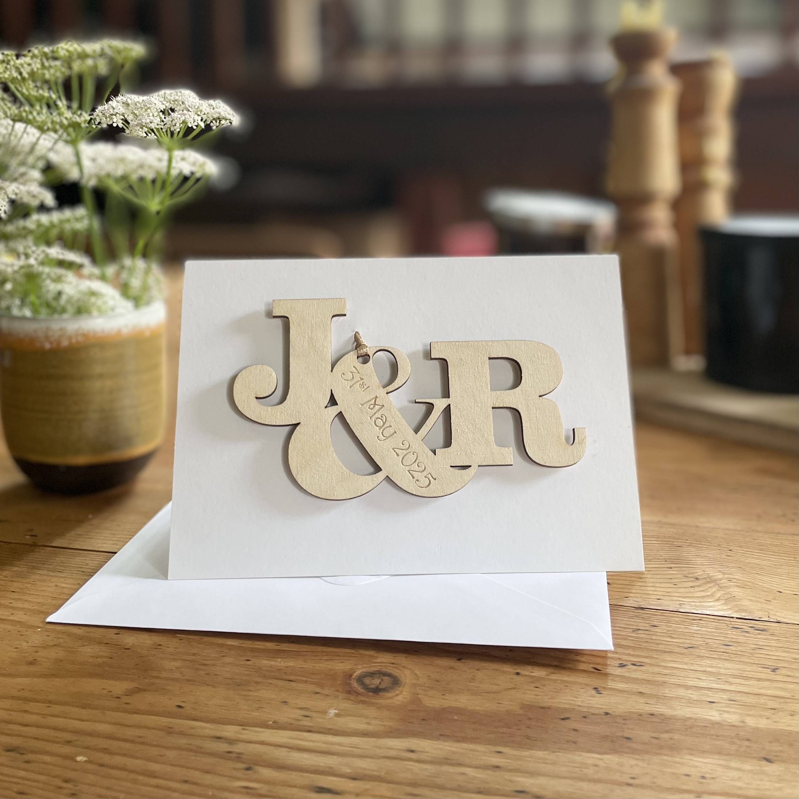 Personalised wooden engagement card with initials and engraved date personalised message on white card.