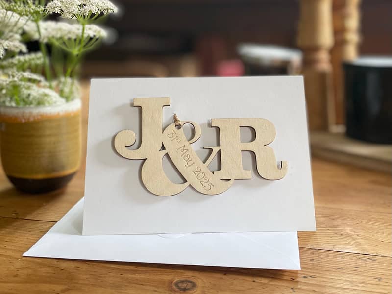 Personalised wooden engagement card with initials and engraved date personalised message on white card.